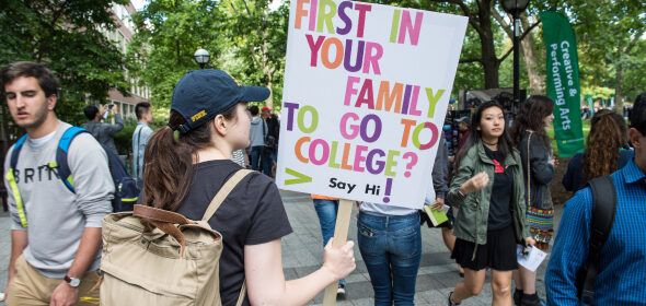 A person with a sign "First in your family to go to college? Say hi!"