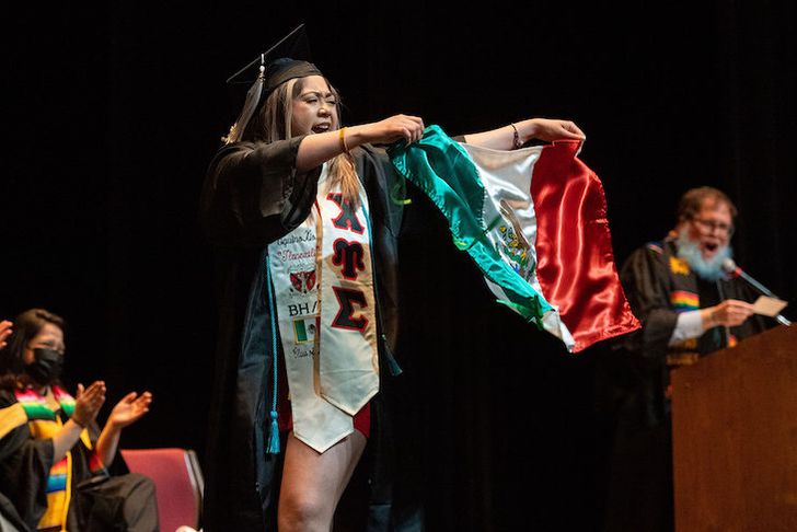 A graduate holding a Mexican flag