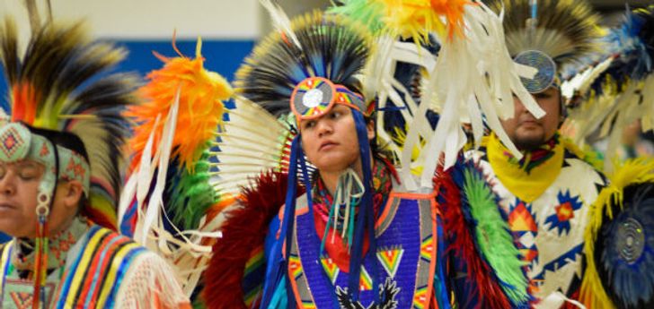 A young person wearing traditional Native American clothing at the Dance for Mother Earth Powwow